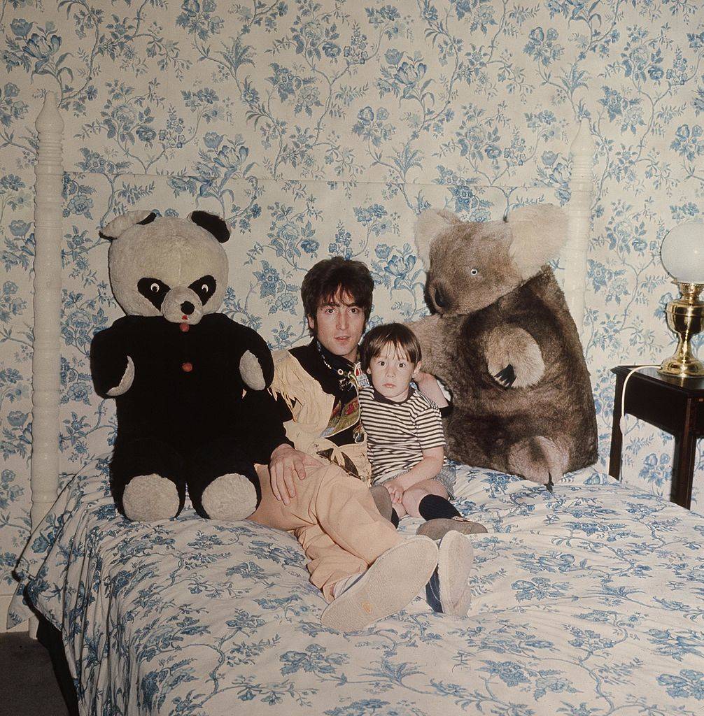 john lennon with his son Julian sitting on a bed with stuffed animals