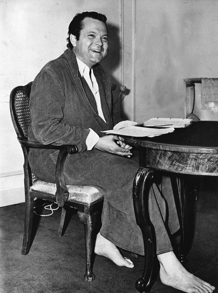 orson welles in his robe sitting at a table