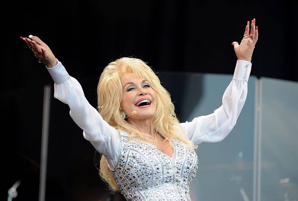 Dolly Parton on stage with her arms raised