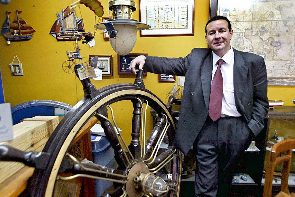 man standing next to ship wheel