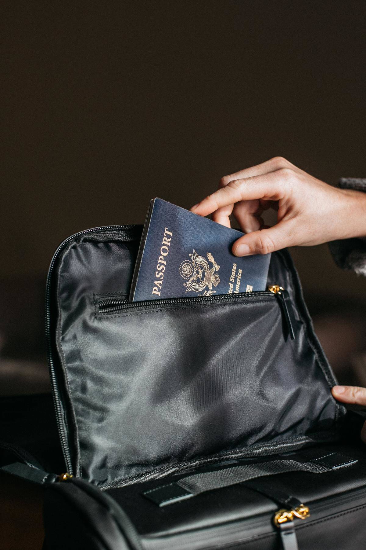 American passport being placed in to zip compartment of bag