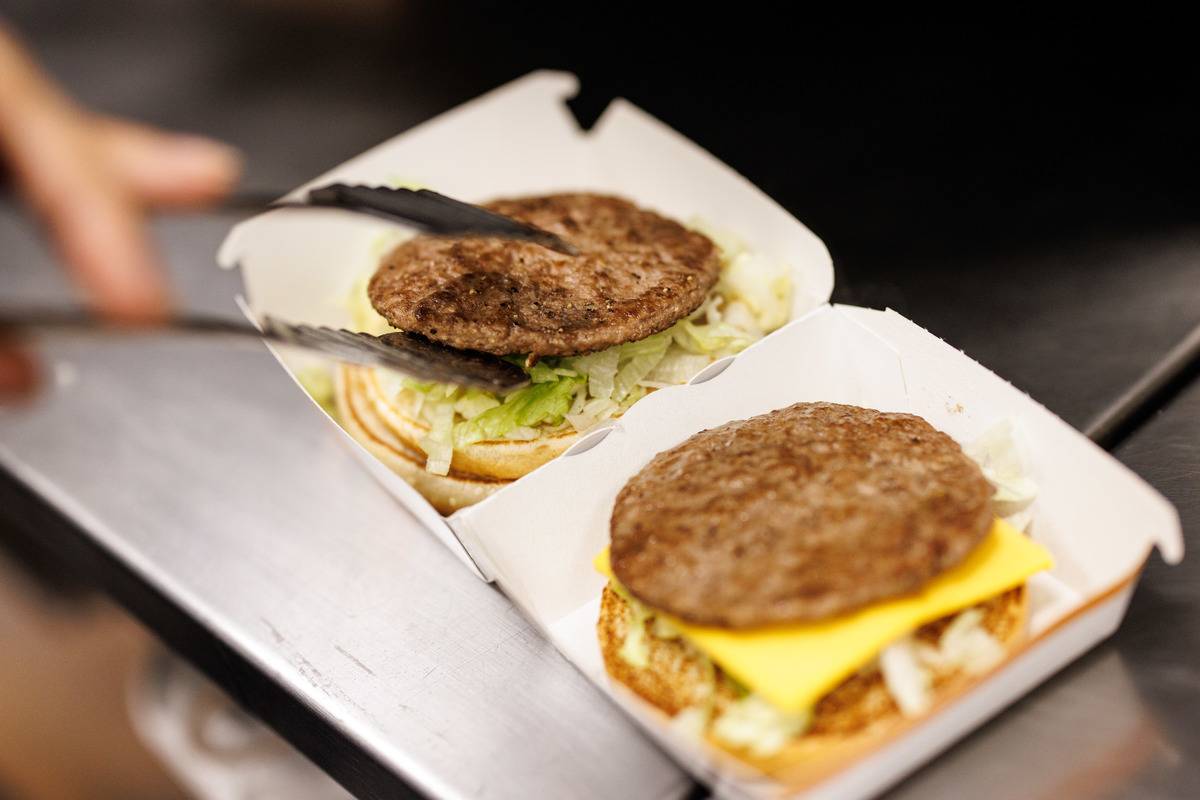 An employee puts a patty on the burger while preparing a Big Mac at a branch of the McDonald's fast food chain