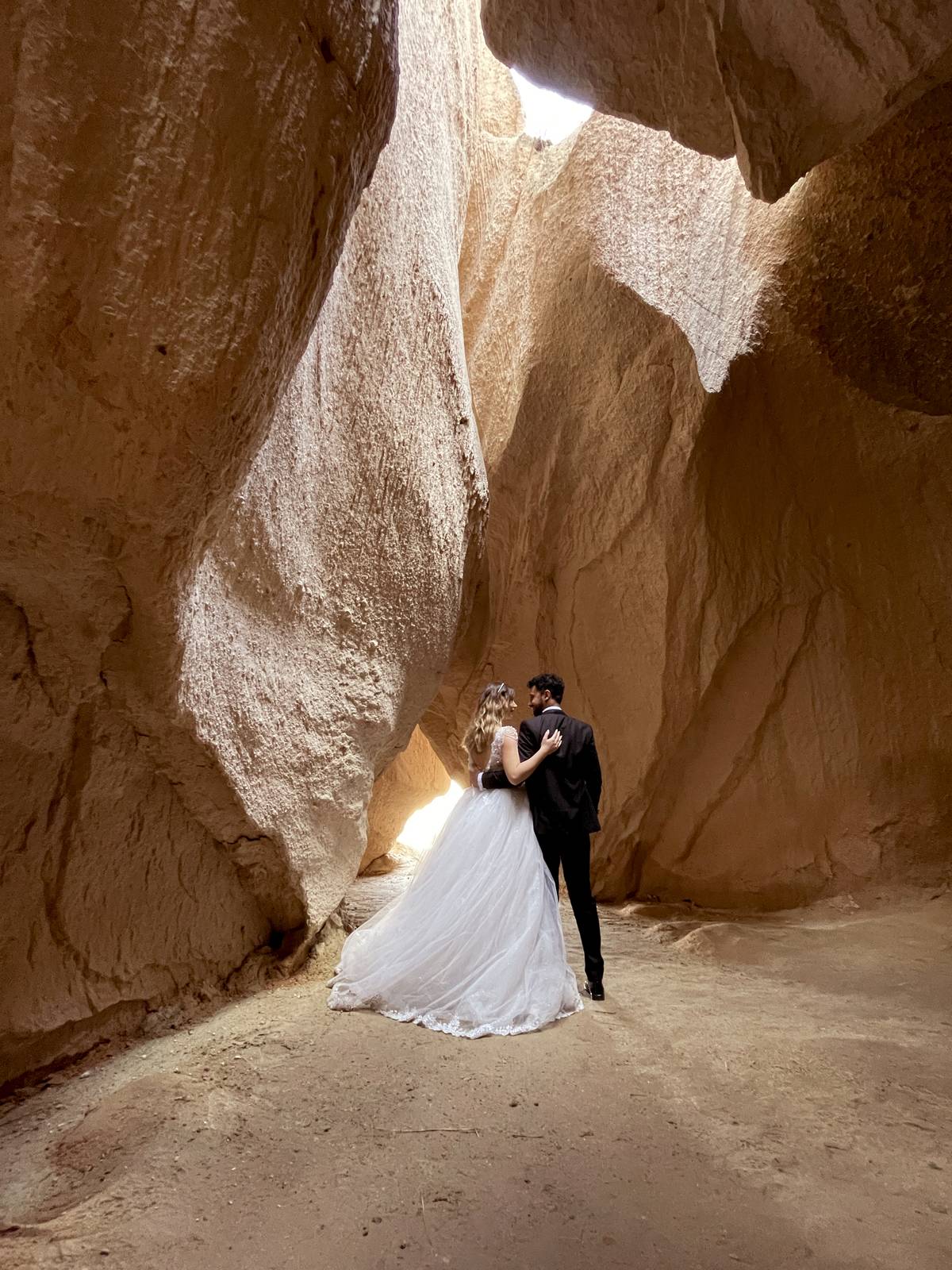 A bride and a groom pose for a photo in a canyon at the historical Cappadocia region, located in Nevsehir province, Turkiye