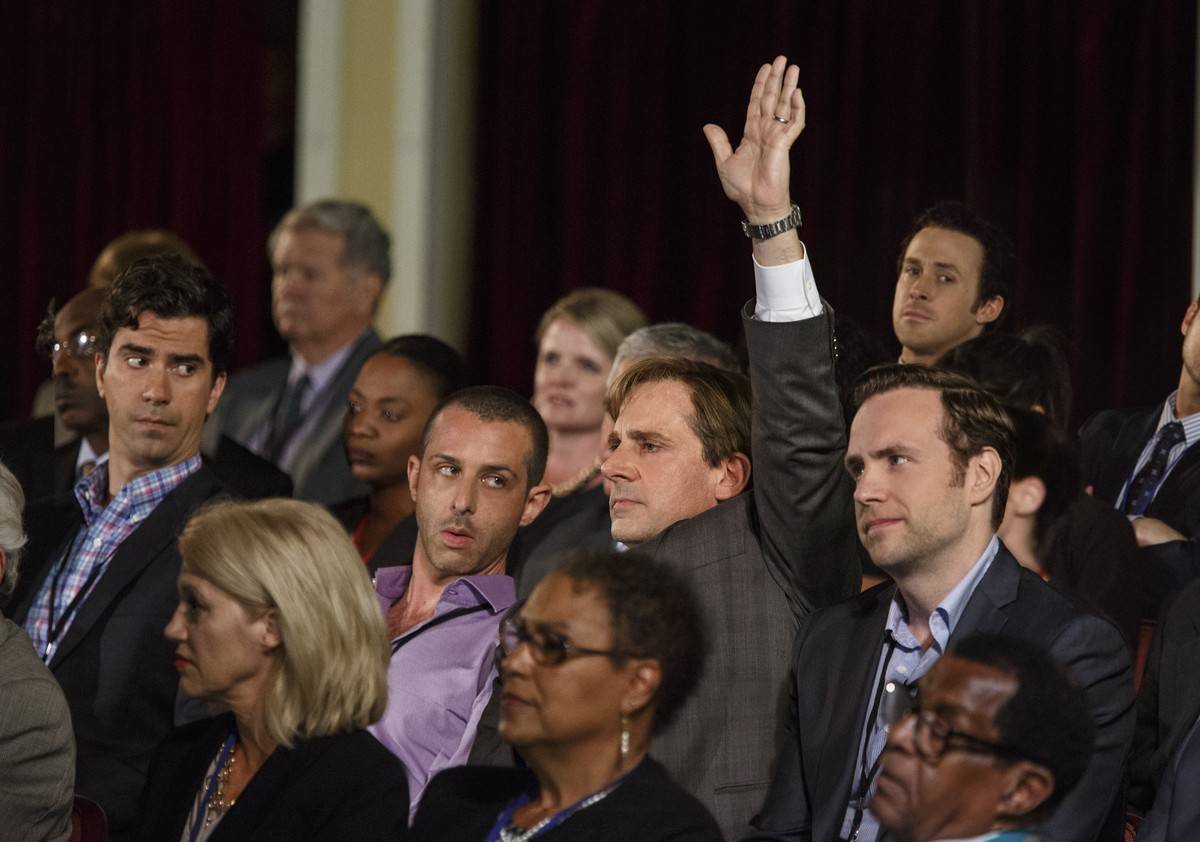 Steve Carell as Mark Baum raising hand at conference in The Big Short