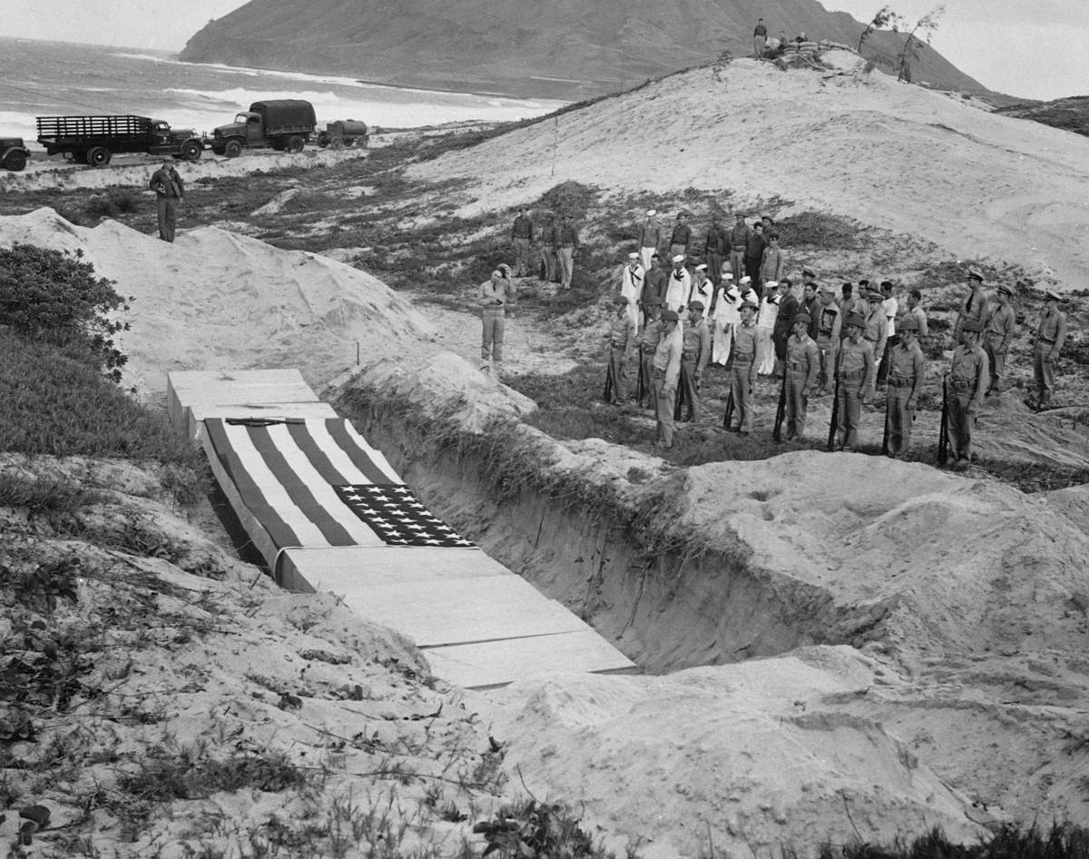 Military personnel pay their respects beside the mass grave of 15 officers and others killed in the attack at Pearl Harbor on December 7, 1941.