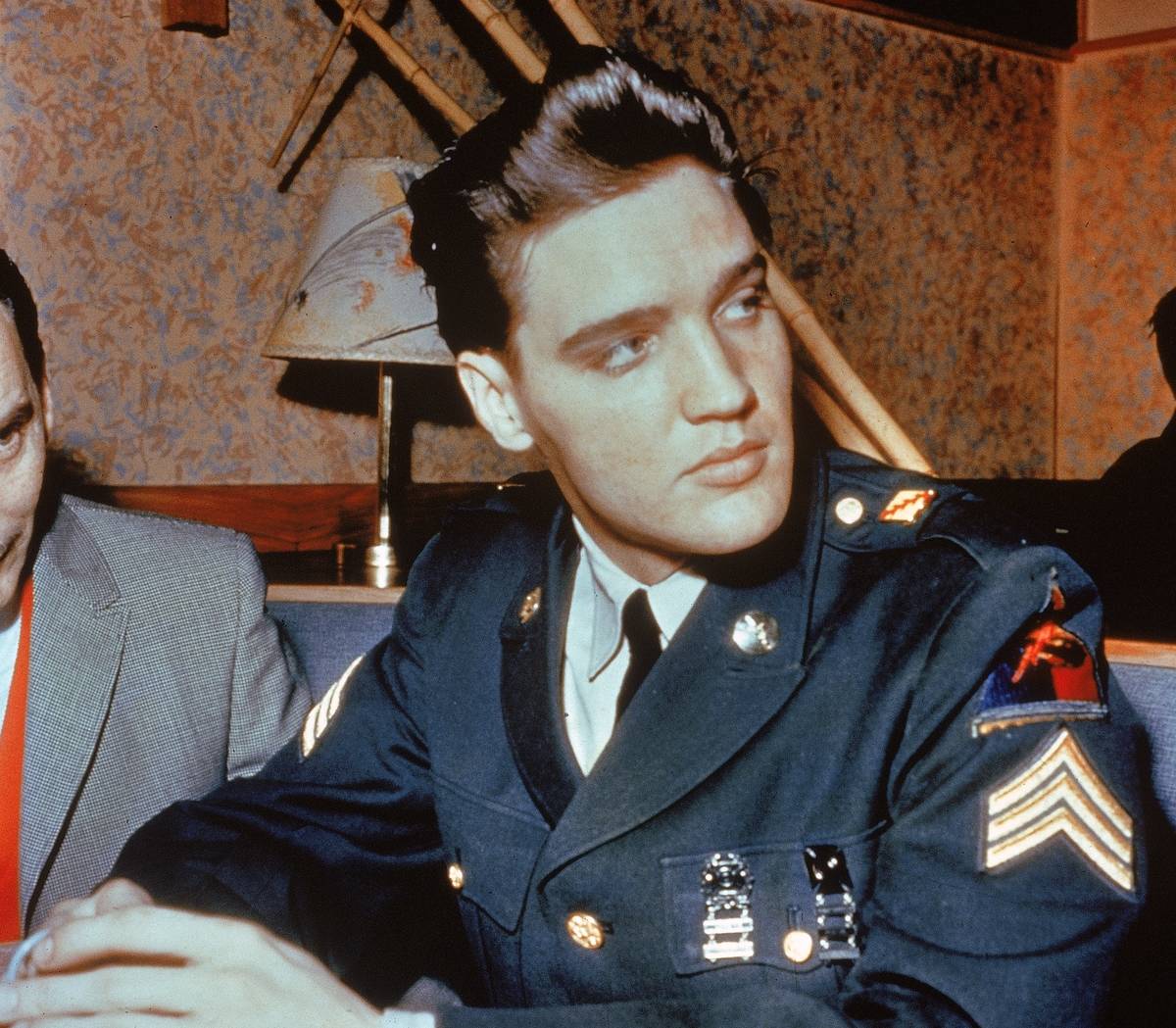 American singer and actor Elvis Presley (1935 - 1977) sits in a restaurant wearing his US Army uniform.