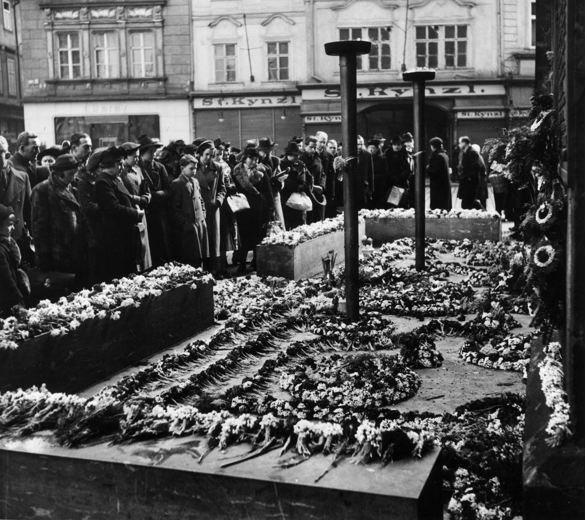 22nd March 1939:  Mourners surround the unknown soldiers tomb strewn with flowers in Prague, Czechoslovakia.