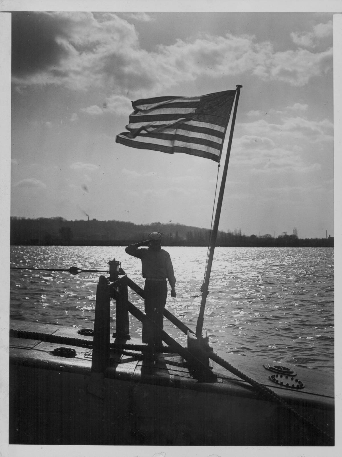 A US sailor saluting the American flag on board a V4 submarine, on the  Potomac River during World War Two, USA, circa 1939-1945.