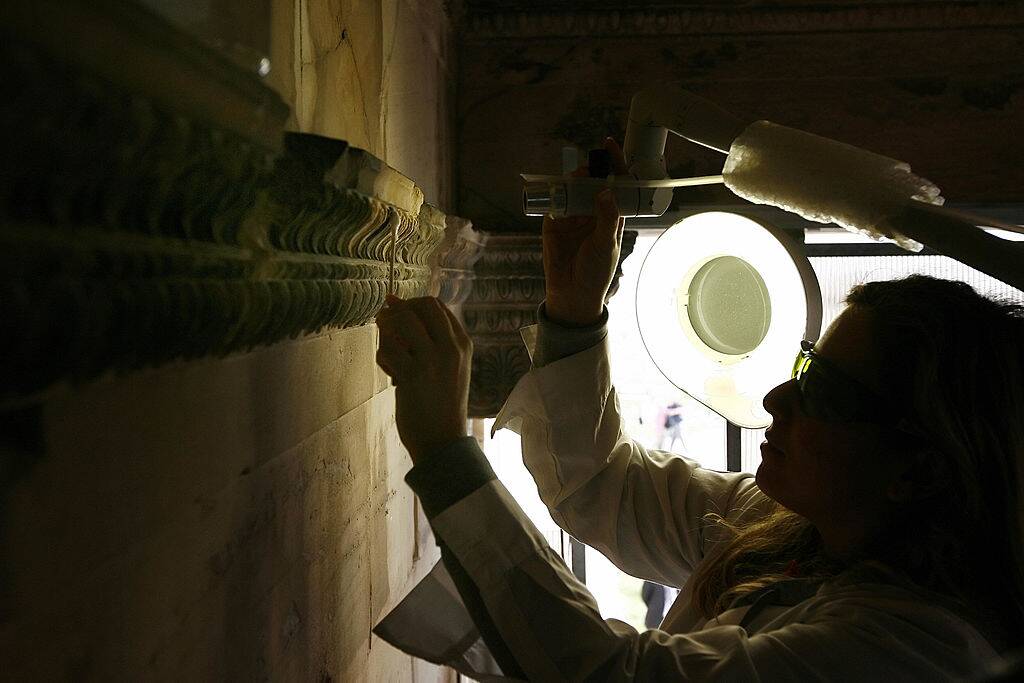 Restorer cleaning temple wall