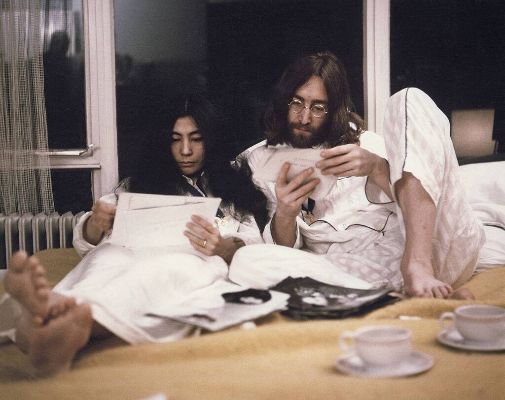 John Lennon and Yoko Ono reading in a bed in 1969