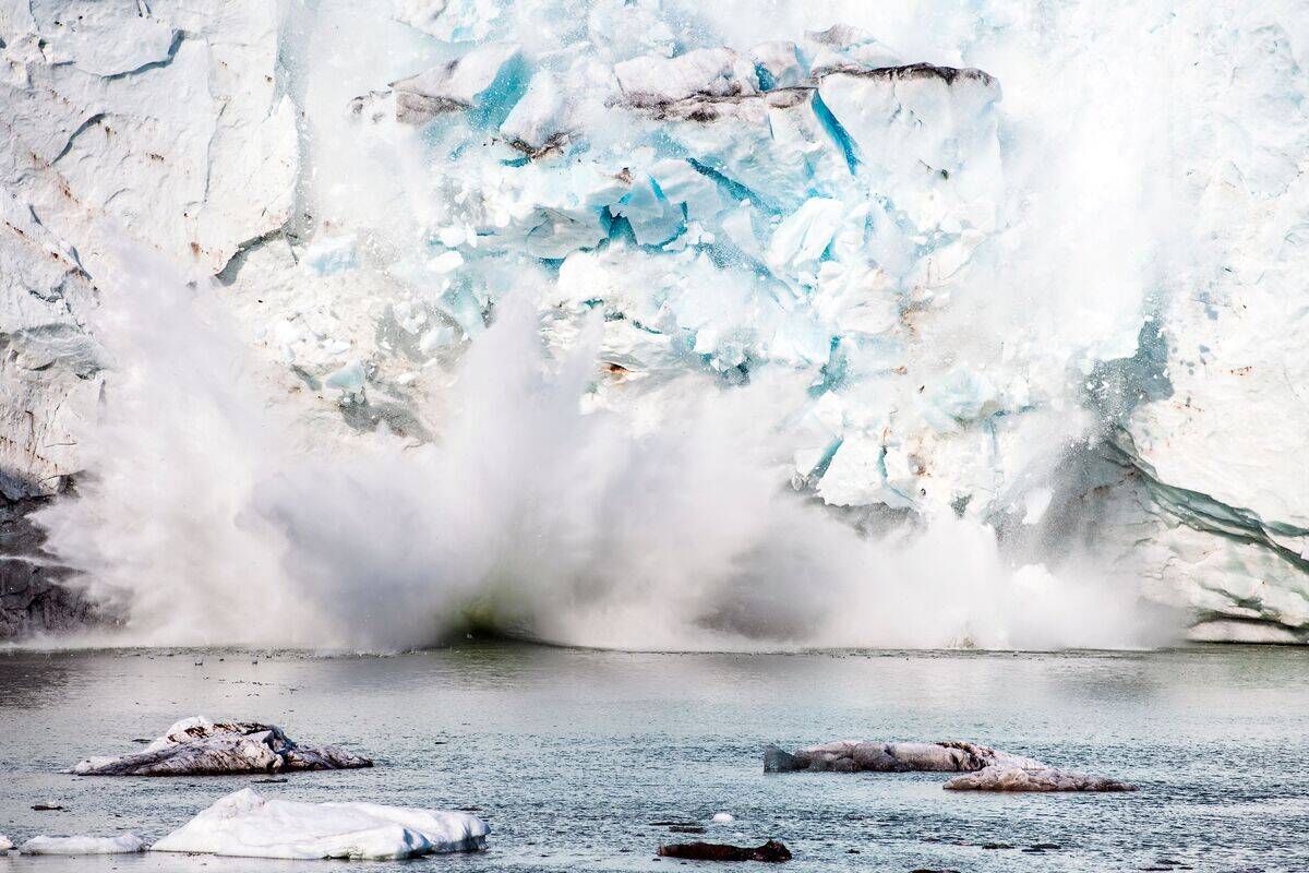 A picture taken on August 17, 2019 shows an iceberg calving with a mass of ice breaking away from the Apusiajik glacier, near Kulusuk (aslo spelled Qulusuk), a settlement in the Sermersooq municipality located on the island of the same name on the southeastern shore of Greenland.