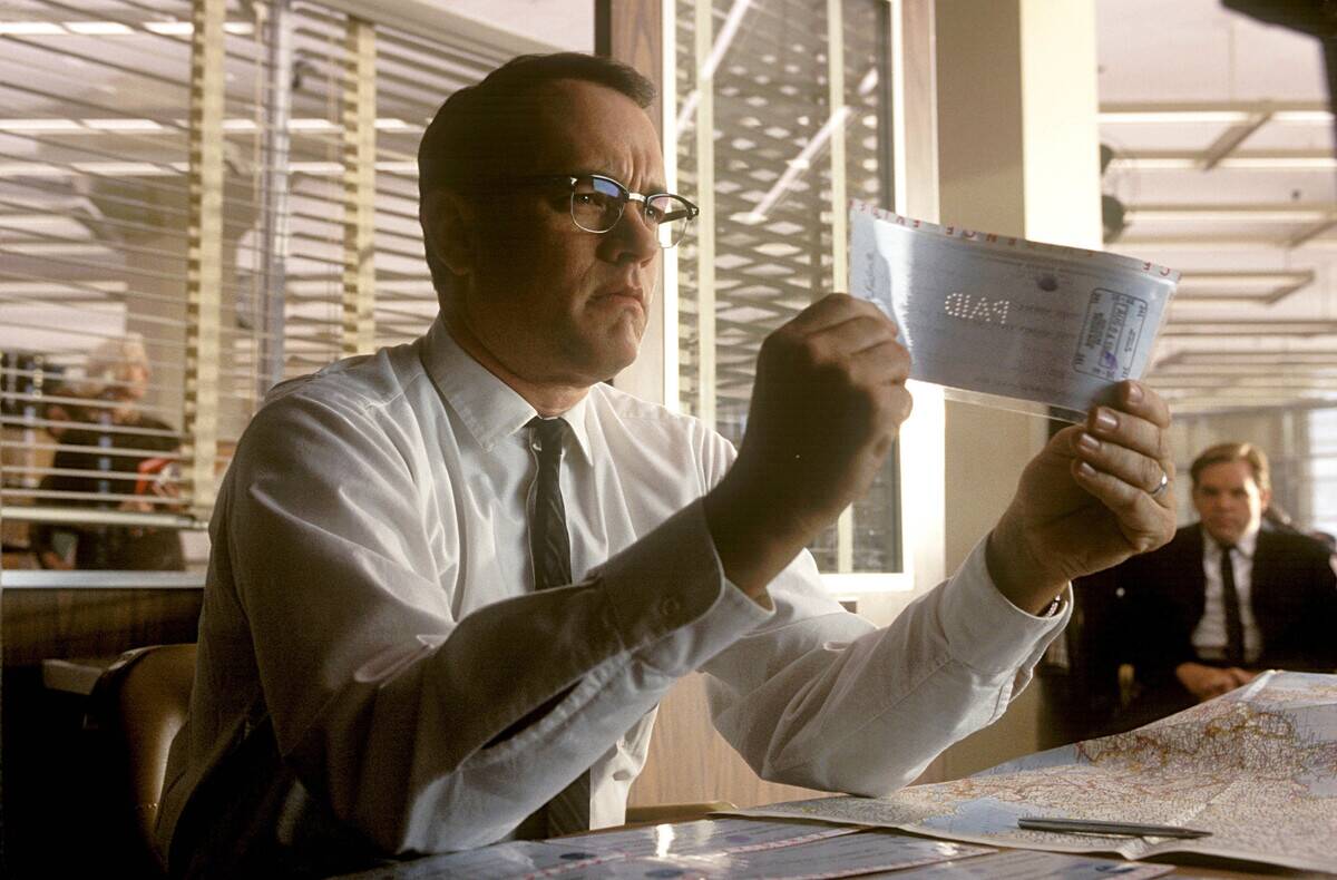 Tom Hanks examining check as Carl Hanratty in Catch Me If You Can