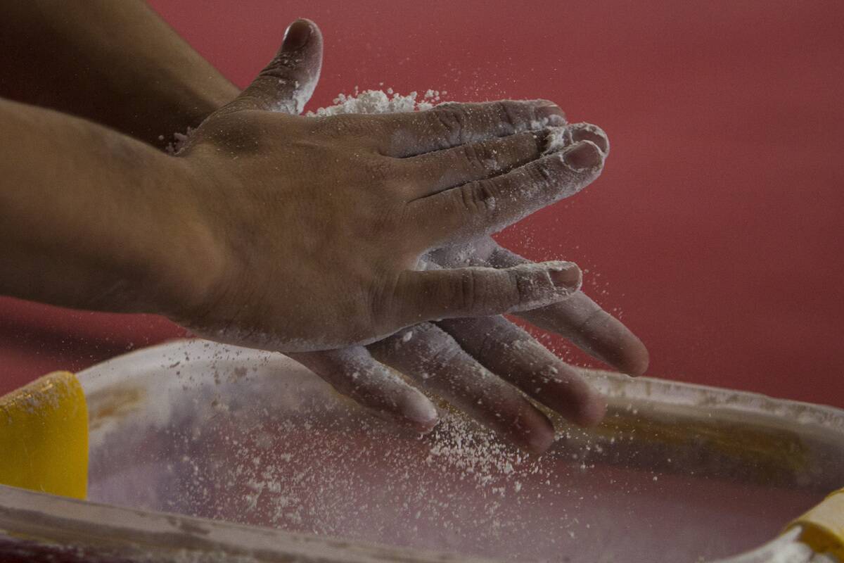 Dilan Jimenez of Colombia dries his hands with magnesium carbonate before competing in parallel bars as part of the I ODESUR South American
Youth Games at Coliseo Miguel Grau on September 26, 2013 in Lima, Peru.