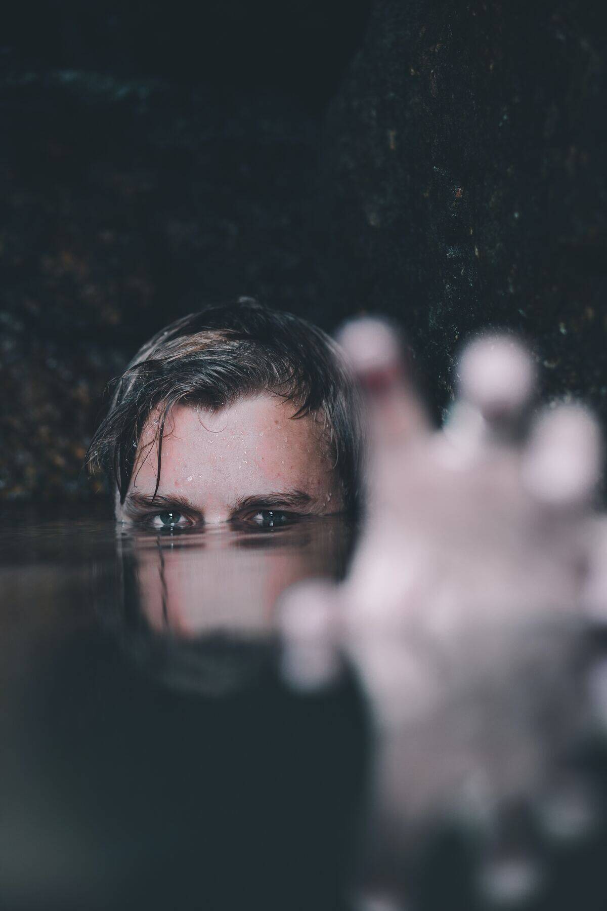 man with eyes and hand above water