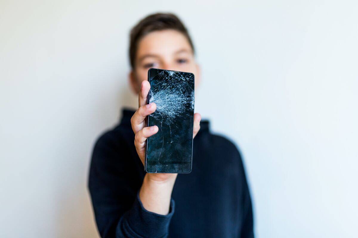 person holding broken phone with cracked screen