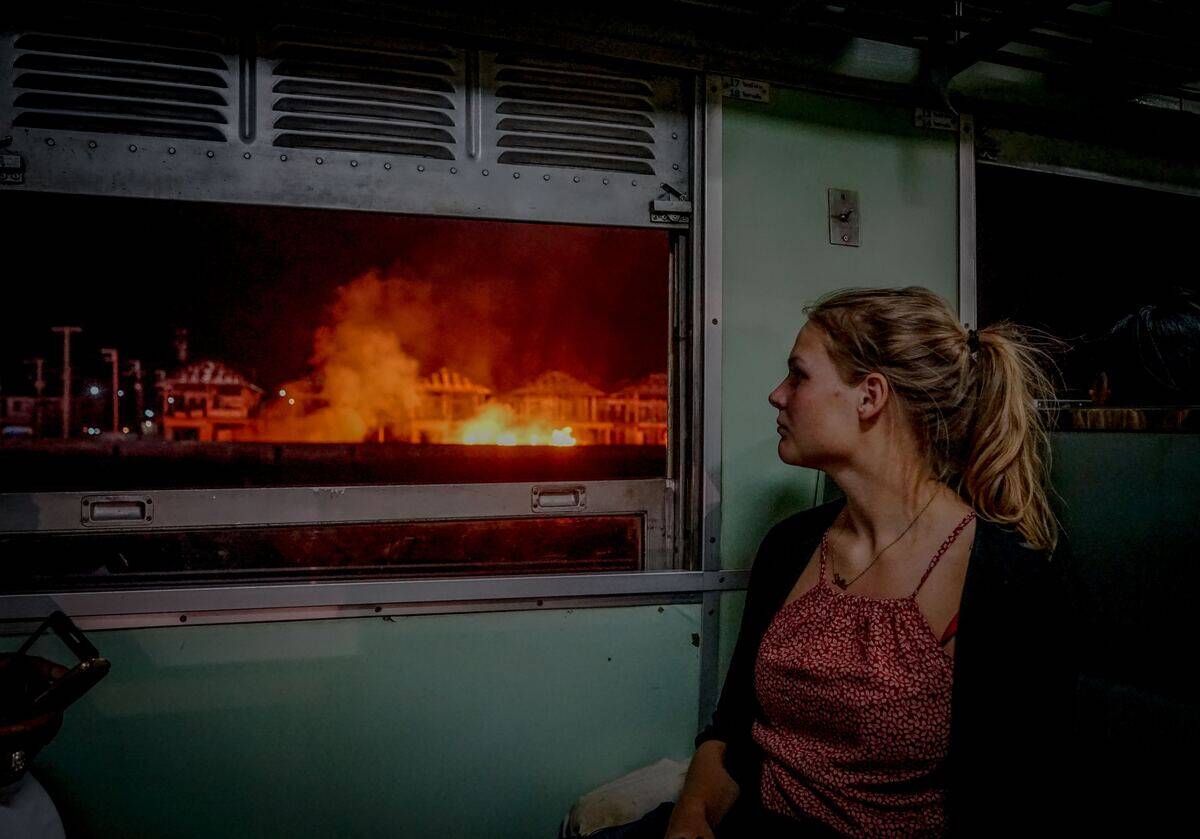 woman looking out train window at fire