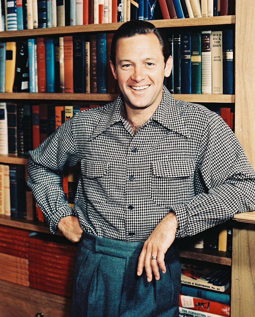 man standing by a bookshelf