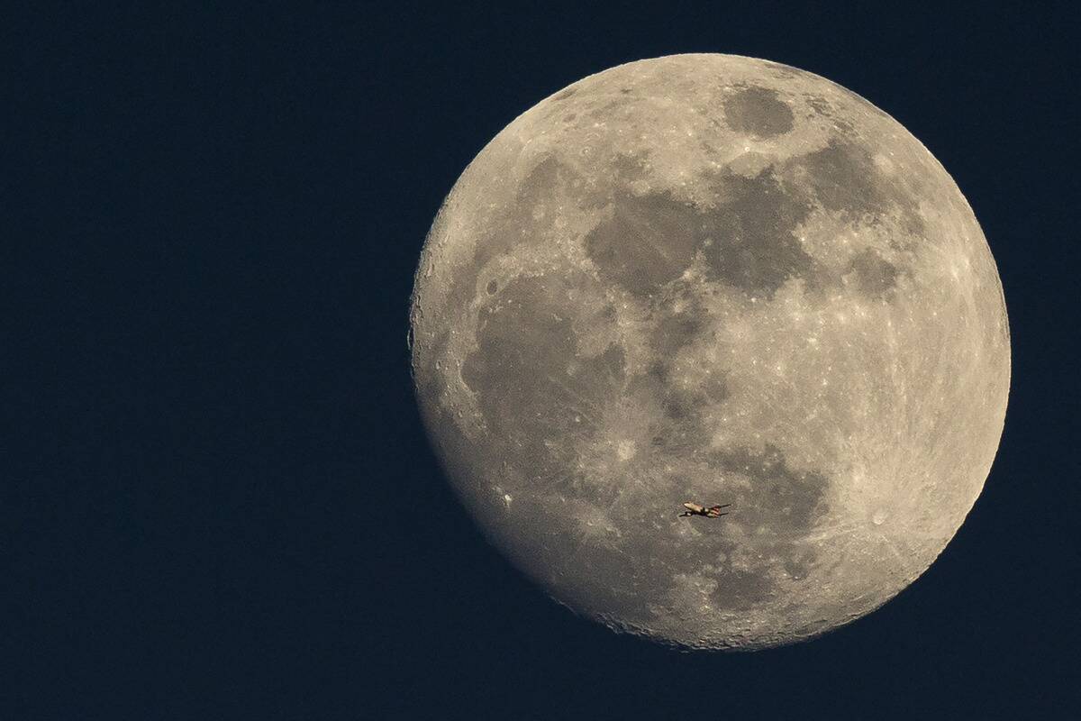 A Plane Is Dwarfed As It Flies Past The Moon