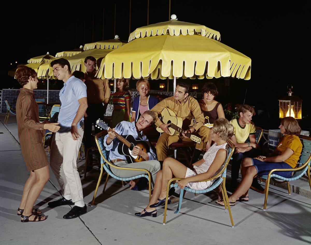 Young adults playing guitar and socializing on patio