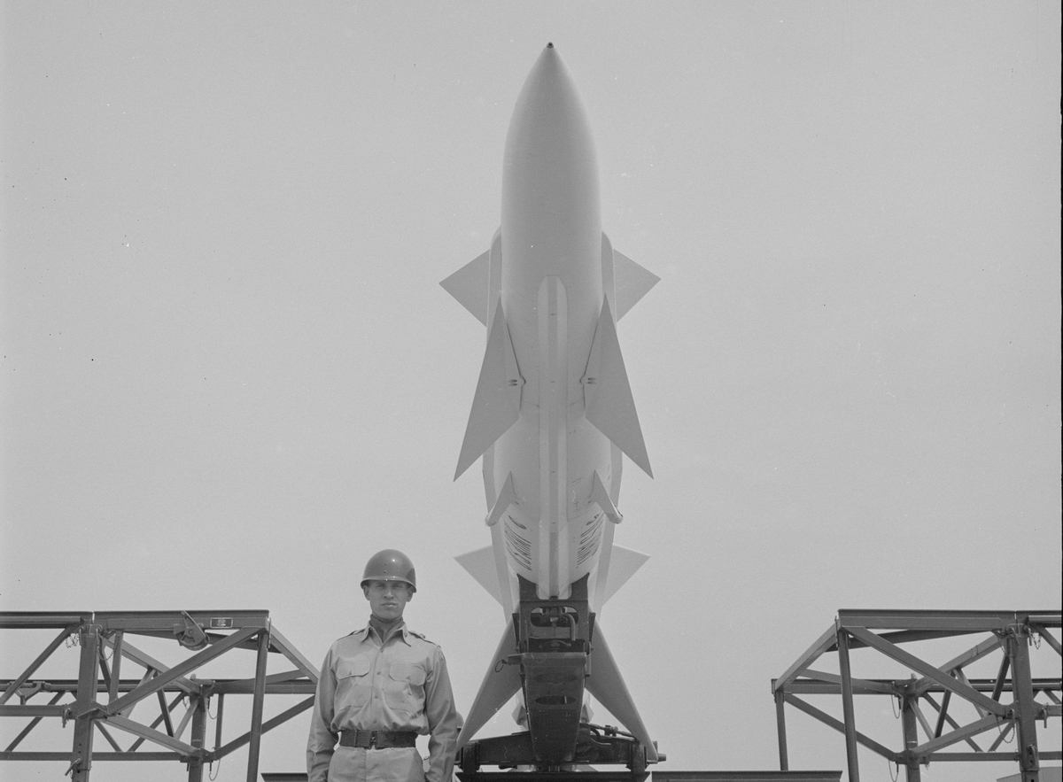 an unidentified American soldier stands under an anti-aircraft missile launcher at a Project Nike