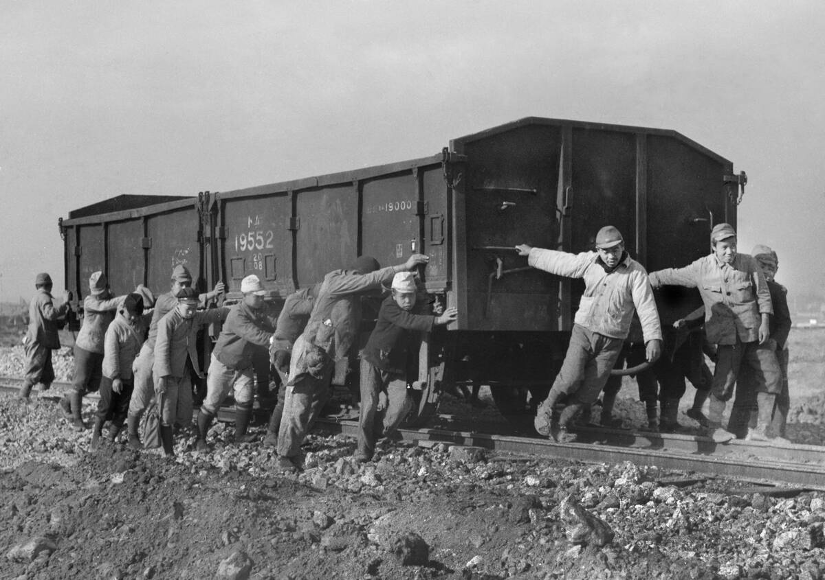 Japanese men haul a freight car by hand, ca. 1949.
