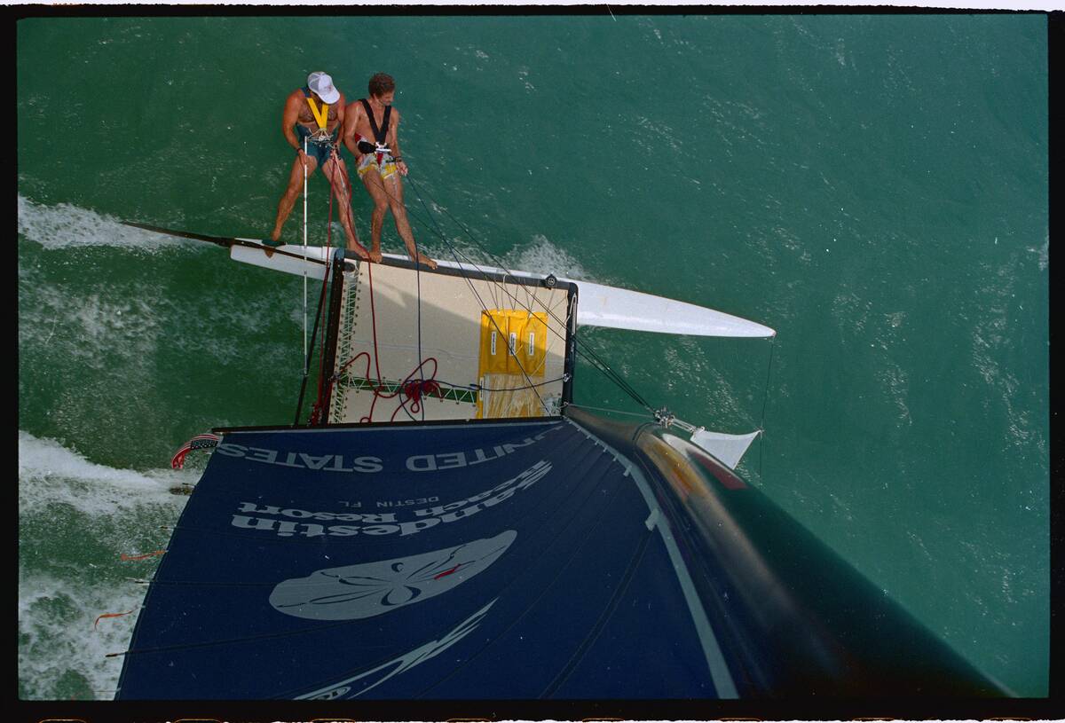 Performers Standing on Trapeezes Aboard Catamaran
