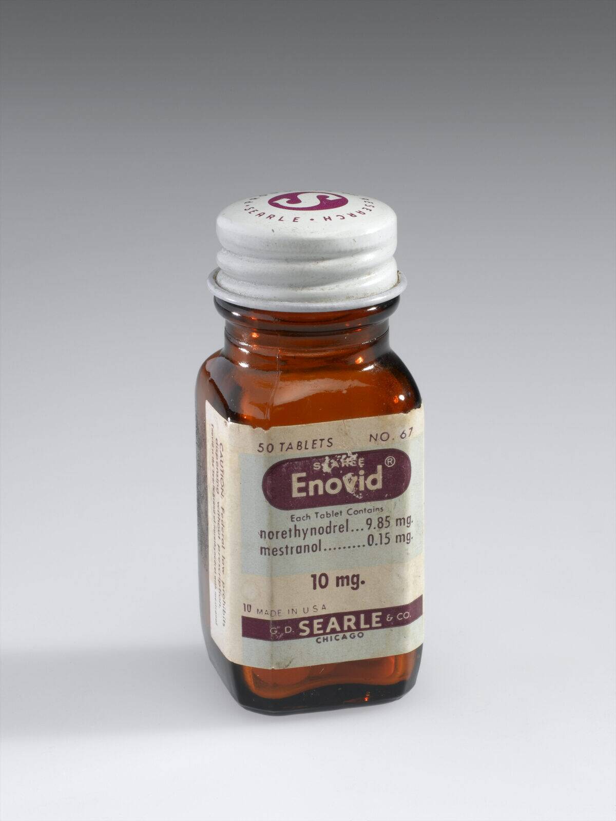 Bottle of Enovid tabs 10mg, early 1960s. Front three quarter view. Graduated grey background.