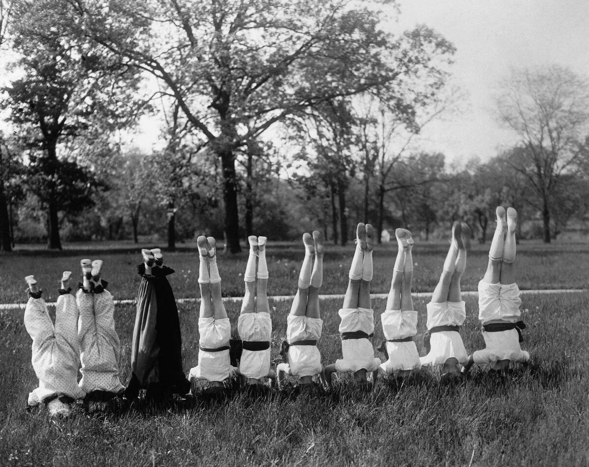 People in row standing on head outdoors