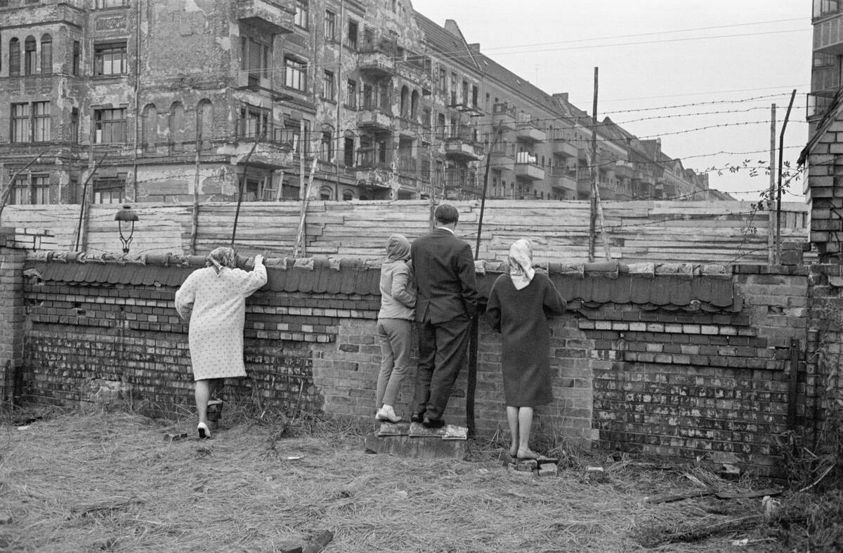 People Look Over Barb Wire at Berlin Wall