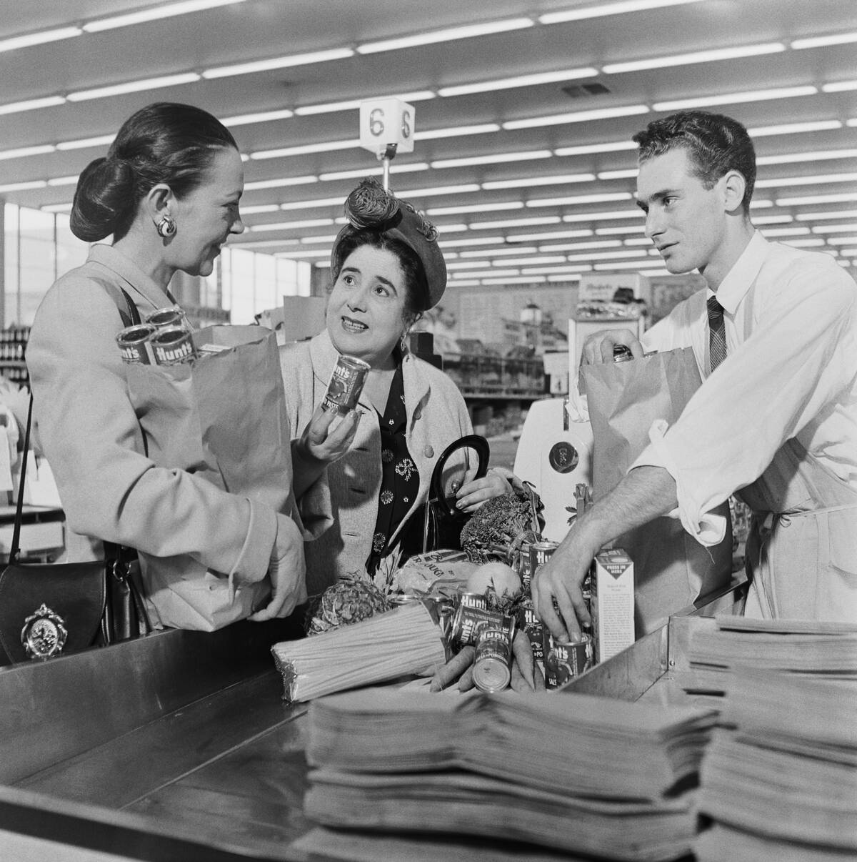 Women standing at checkout counter, shop assistant packing