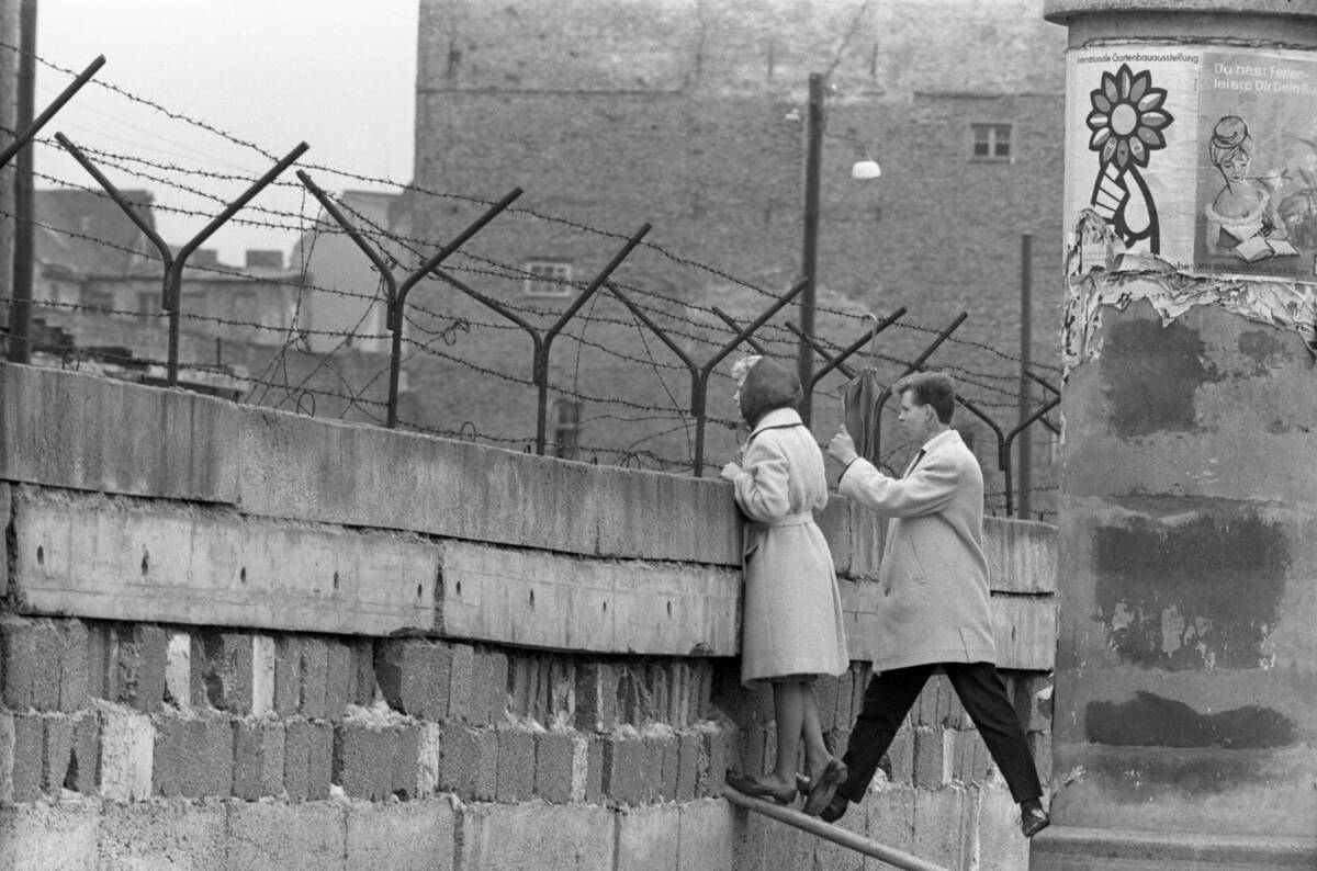 Young Couple Peers Over Berlin Wall