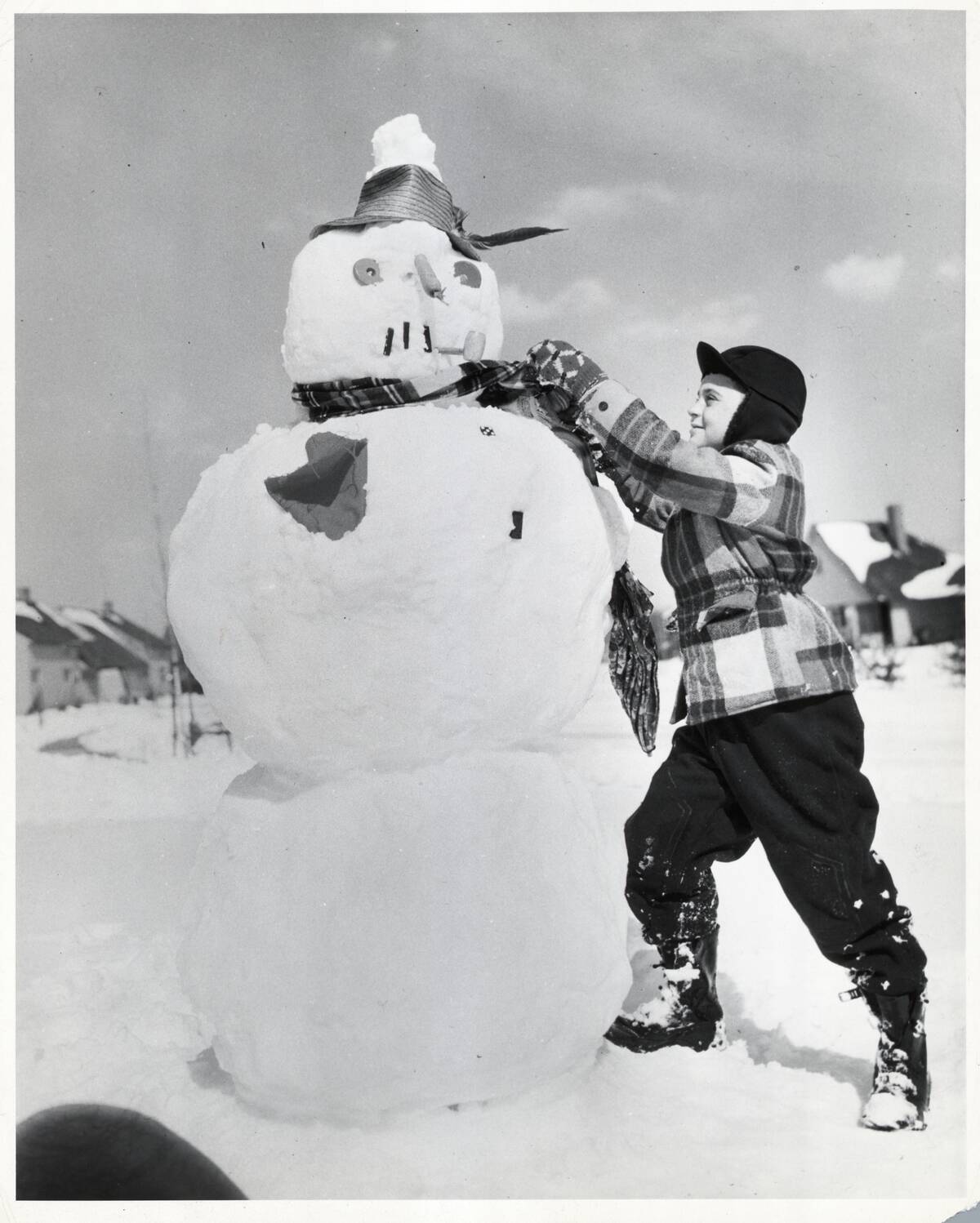 Boy Tying Scarf Around Snowman