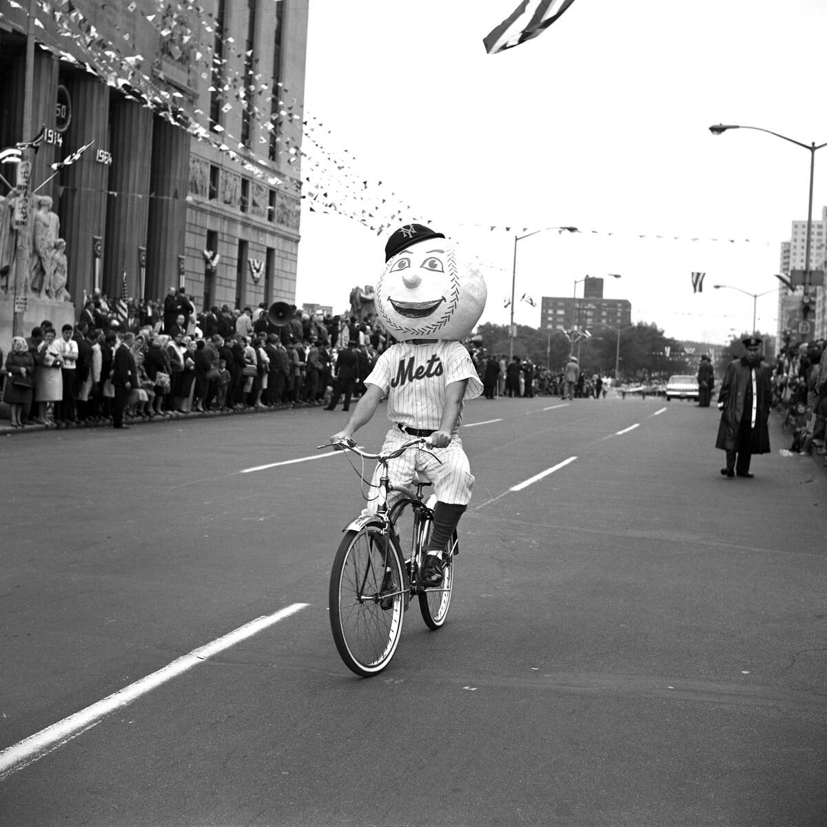 Out of his element, Mr. Met on a bicycle rides in parade on