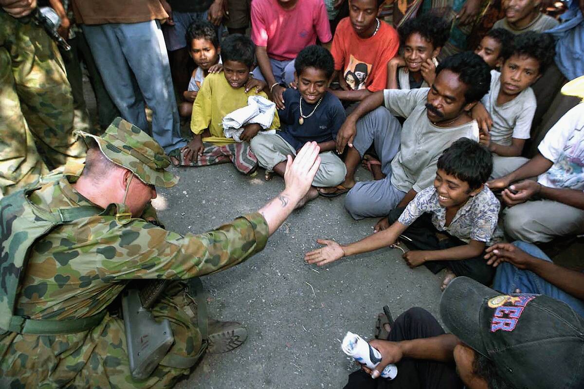 Australian peacekeeper Daniel Stewart (L) plays wi