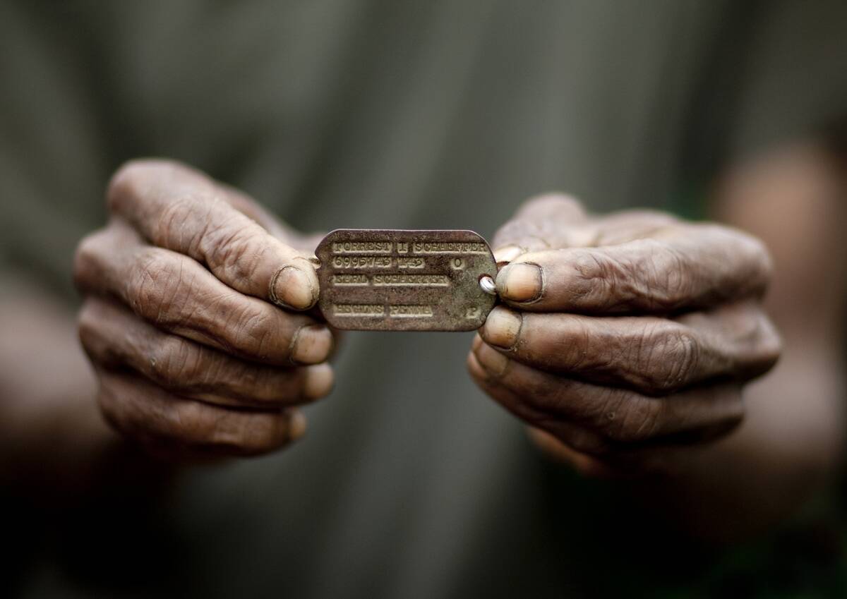 Man holding a WW2 Dog Tag, Milne Bay Province, Trobriand Island, Papua New Guinea...