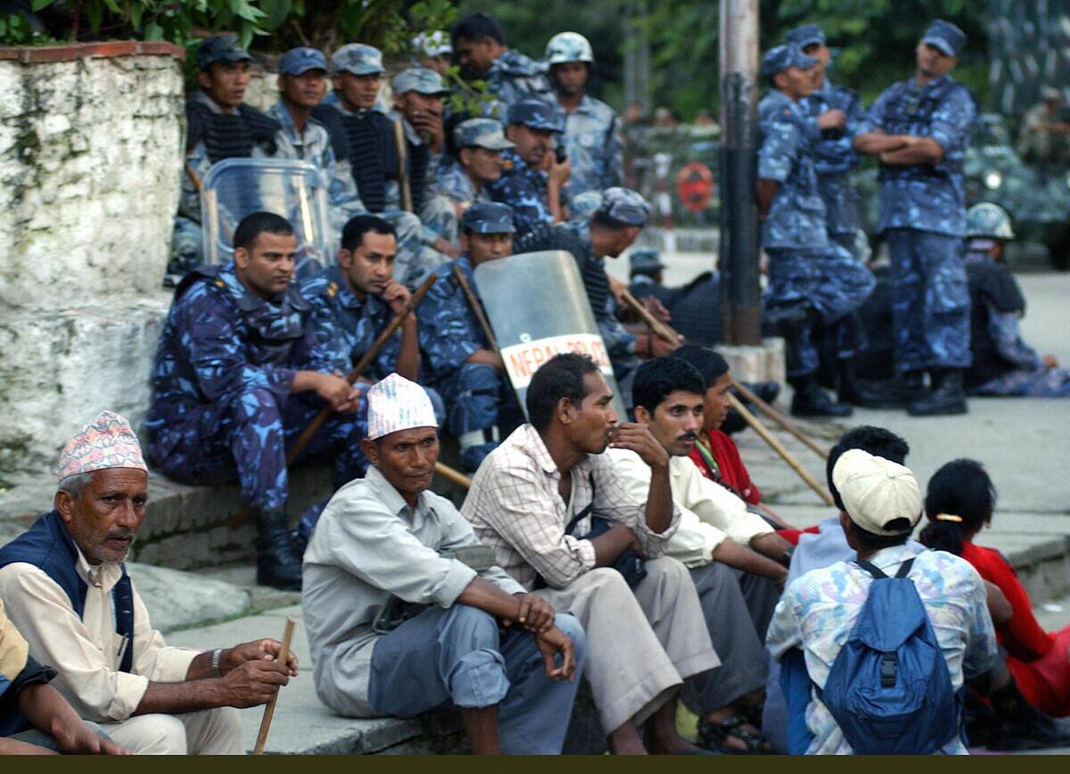 Riot police sit behind participants duri