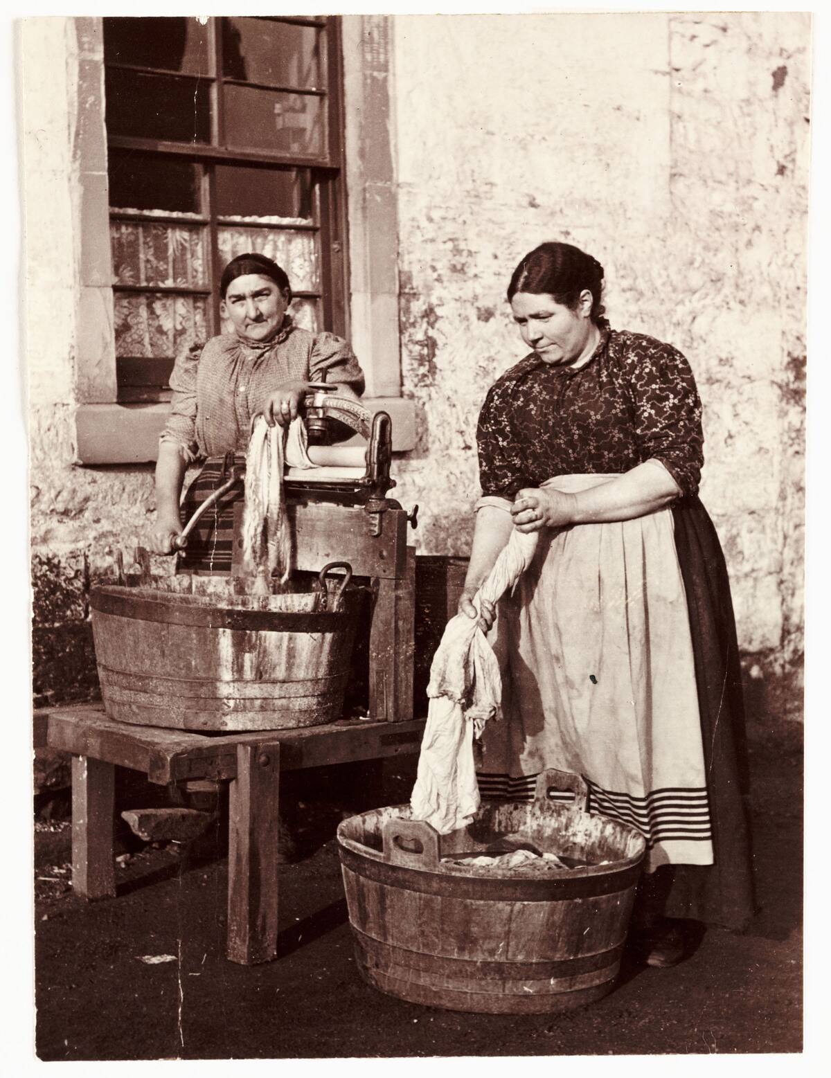 Two women washing clothes, c 1905.
