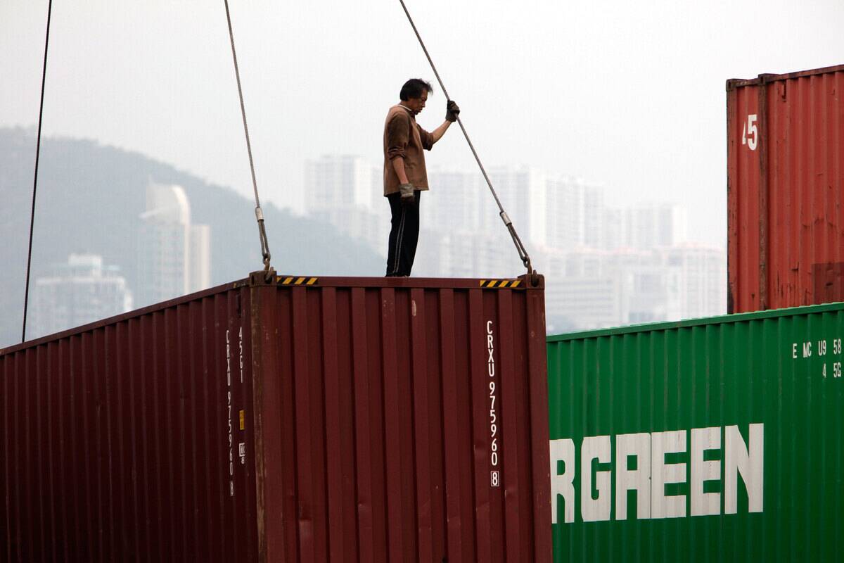 Workers load containers in a cargo facility in the Kwun Tong