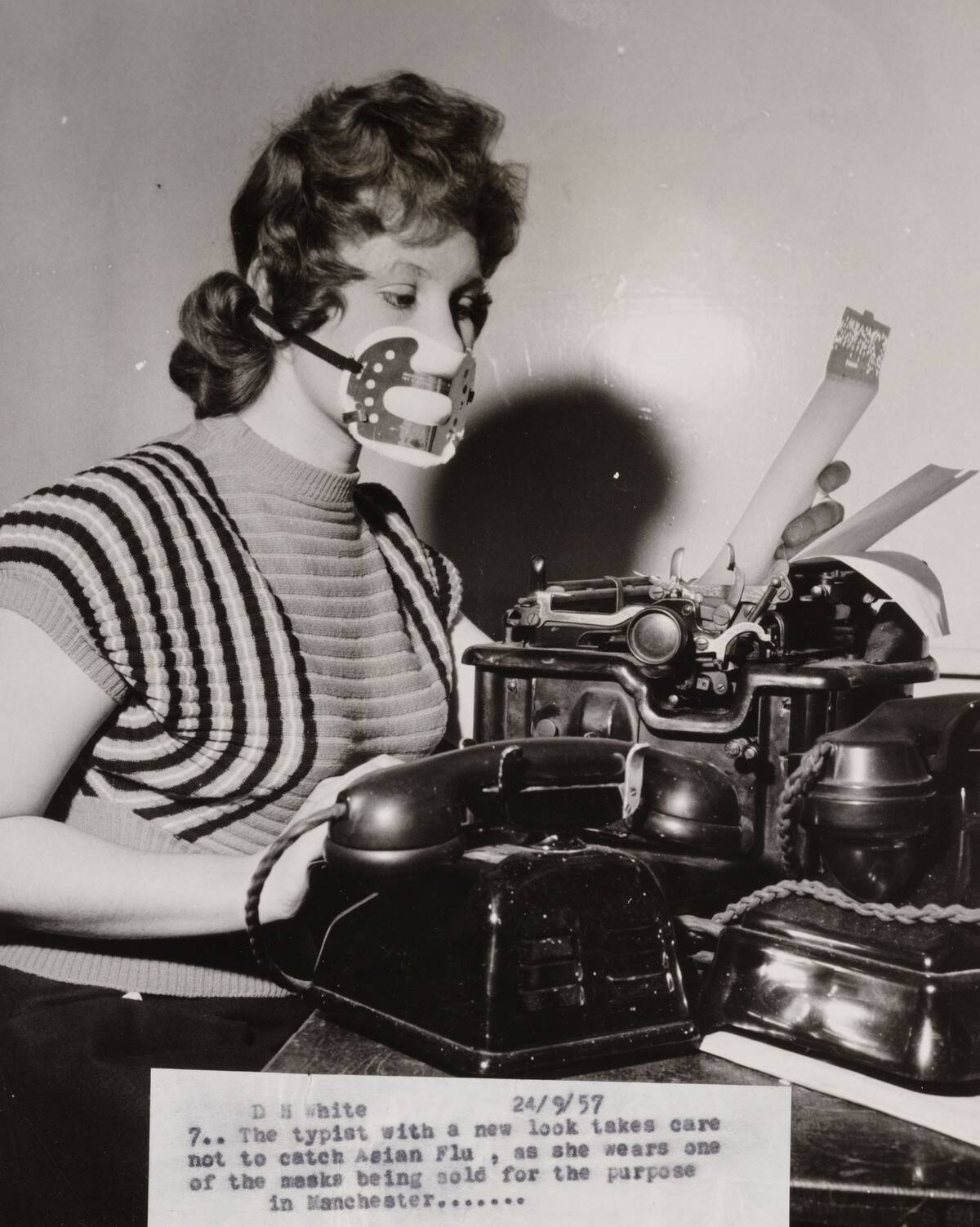 'A typist wears a mask to protect against Asian flu', 24 Sept 1957.