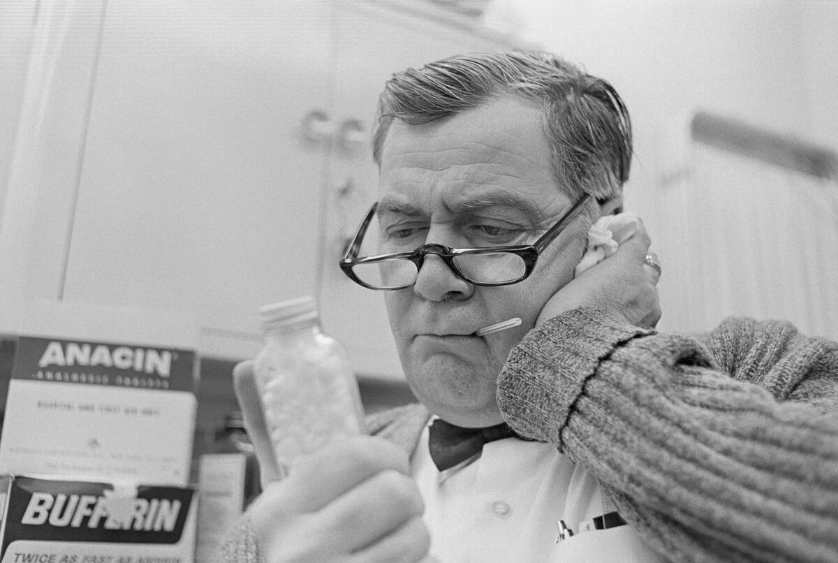Man Holding Pills While Taking His Temperature
