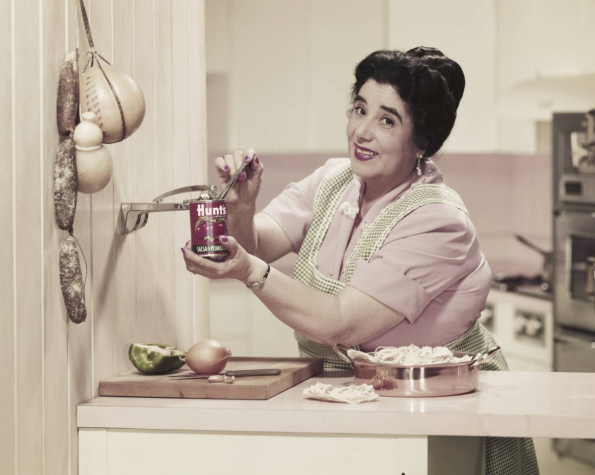 Mature woman opening tin can while preparing food