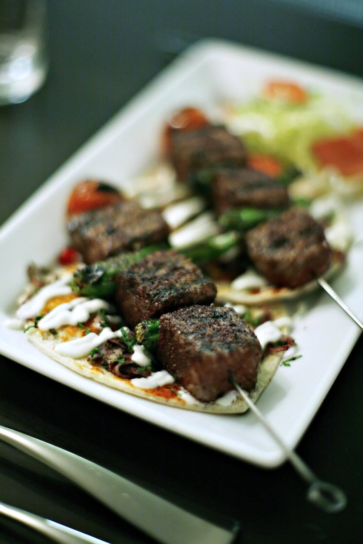 A plate of seared Kobe beef with mustard-hummus sauce is arr