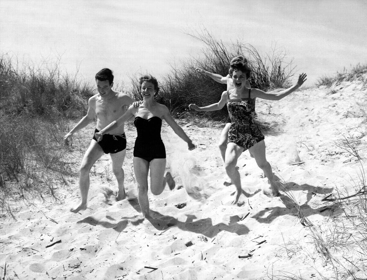Friends chasing each other at the beach in Ostend during a day out at the seaside circa 1955