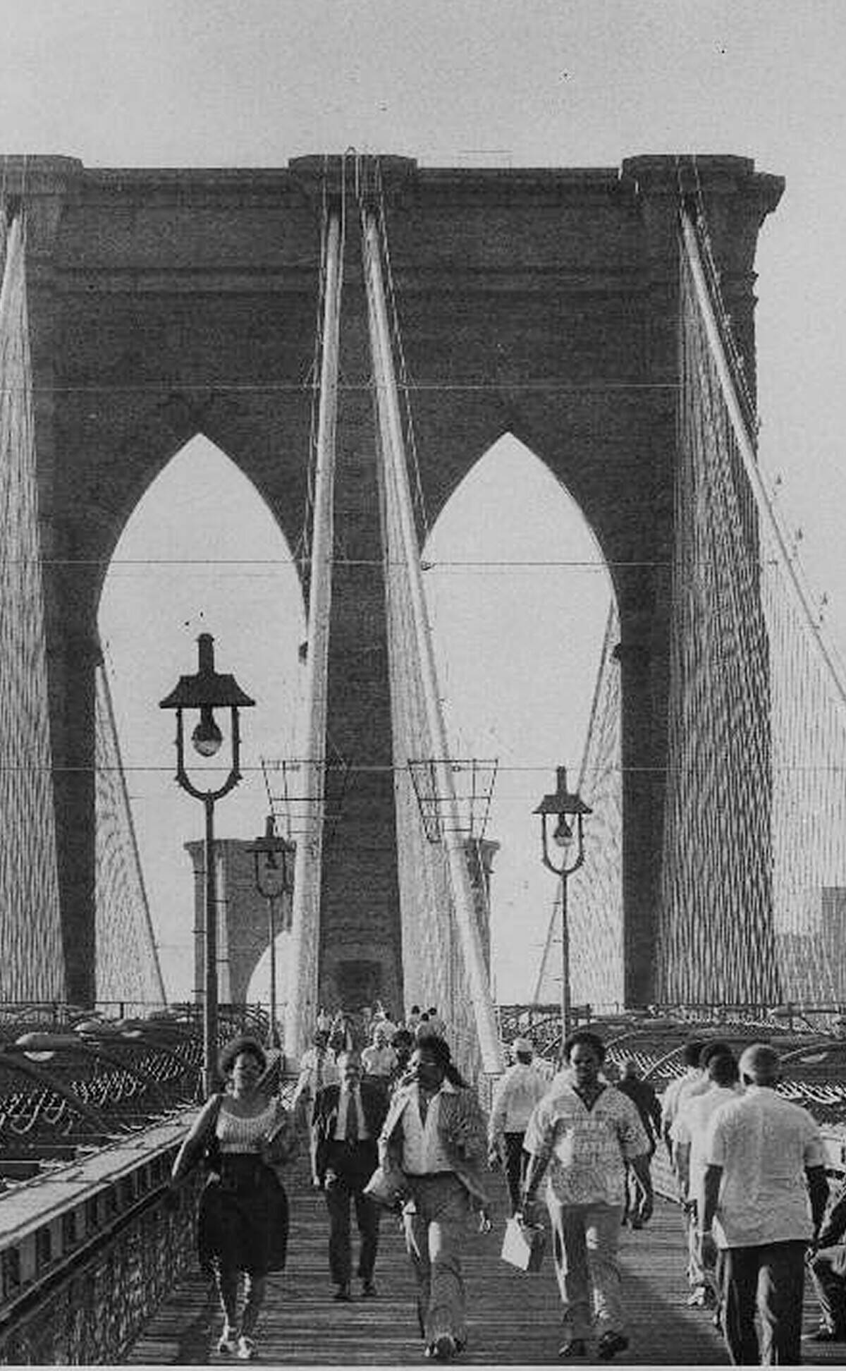 People walk across the Brooklyn Bridge from Brooklyn to Manh