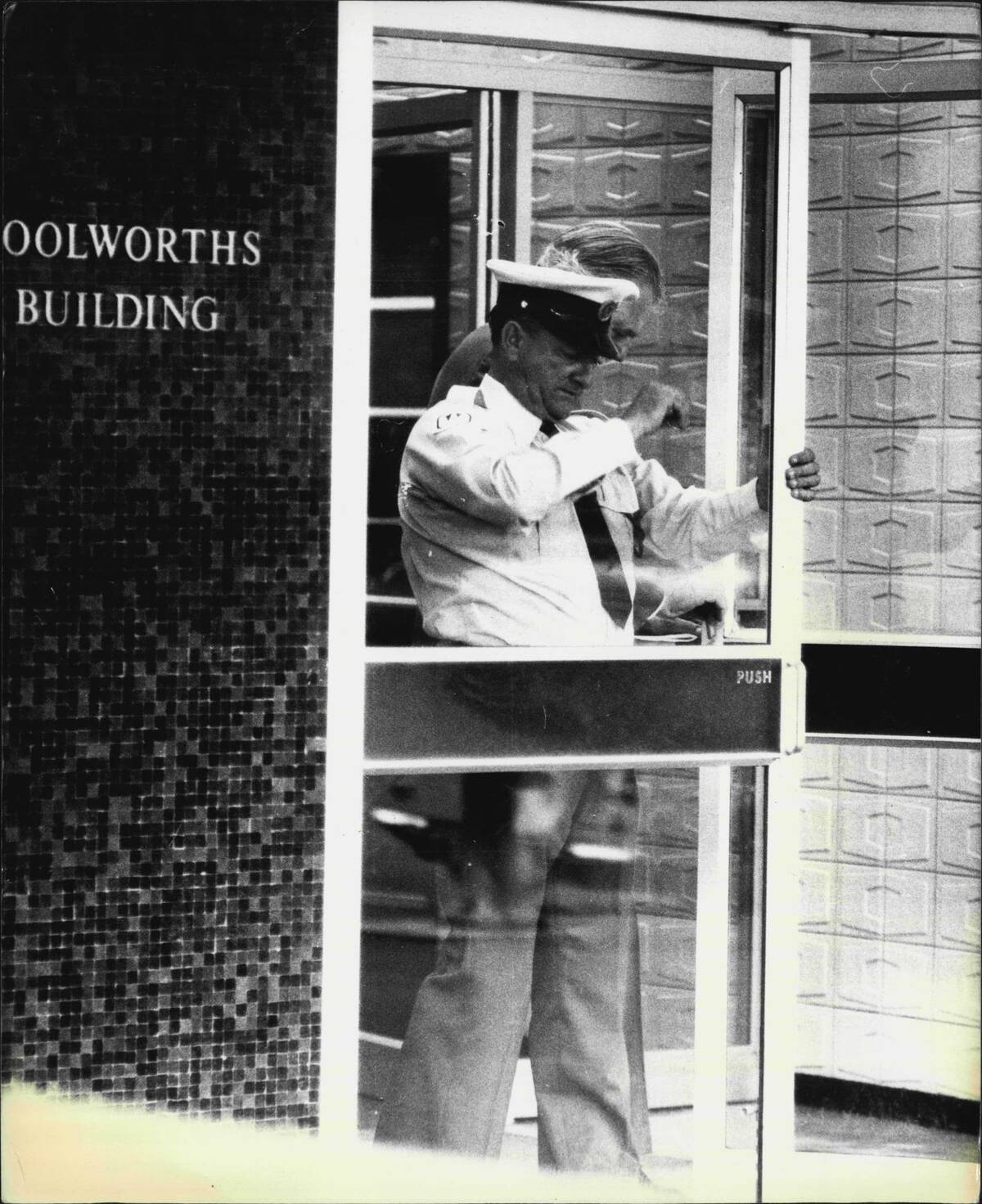 Pictures of a security Guard at the door of the main entrance to Woolworths main office in George St. next to their Town Hall store.