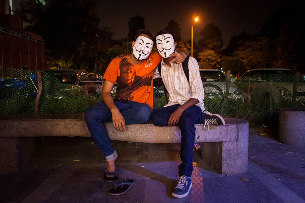 Two young men wearing the Guy Fawkes mask, symbol of the...