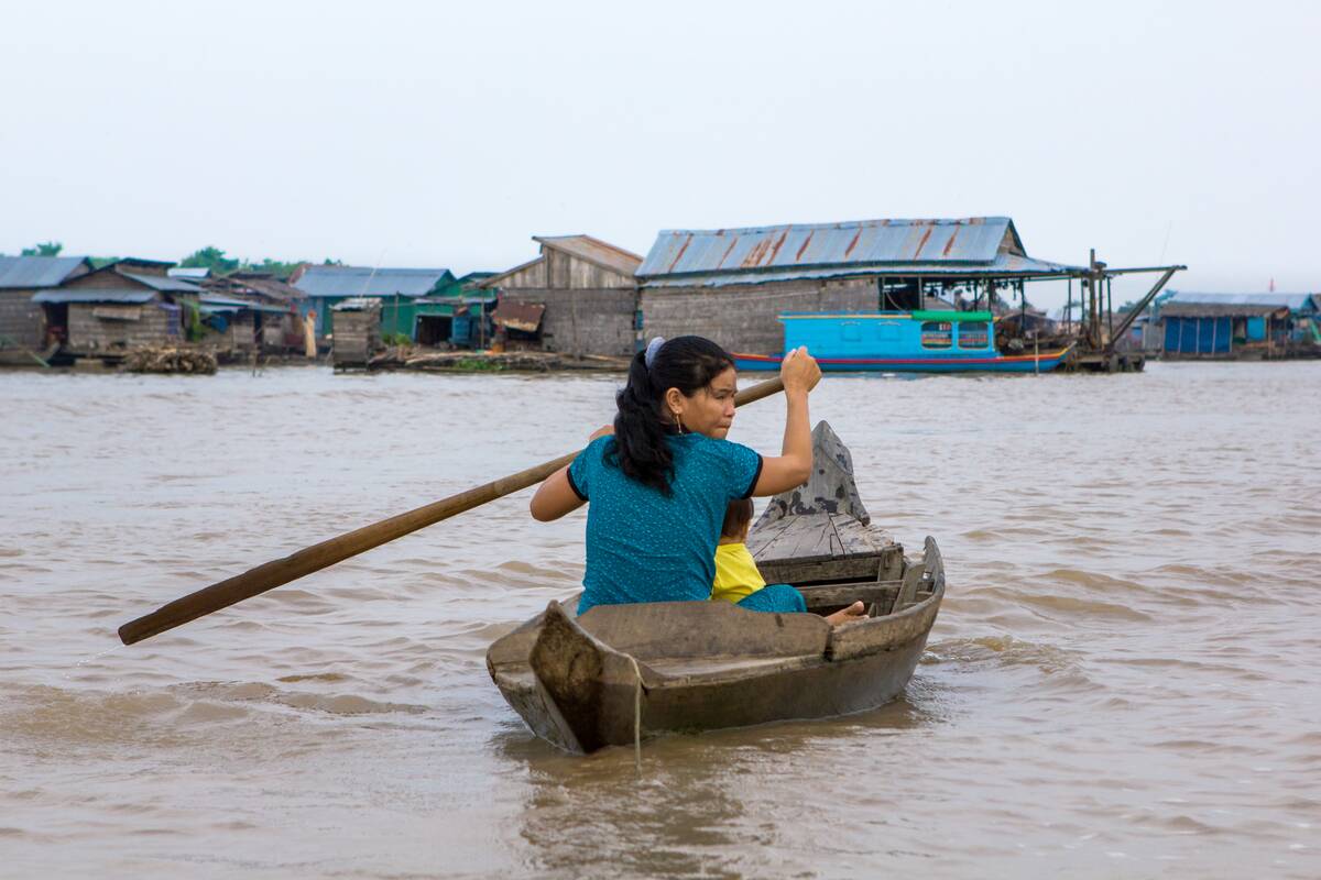 Woman in rowing boat at floating village, Cambodia