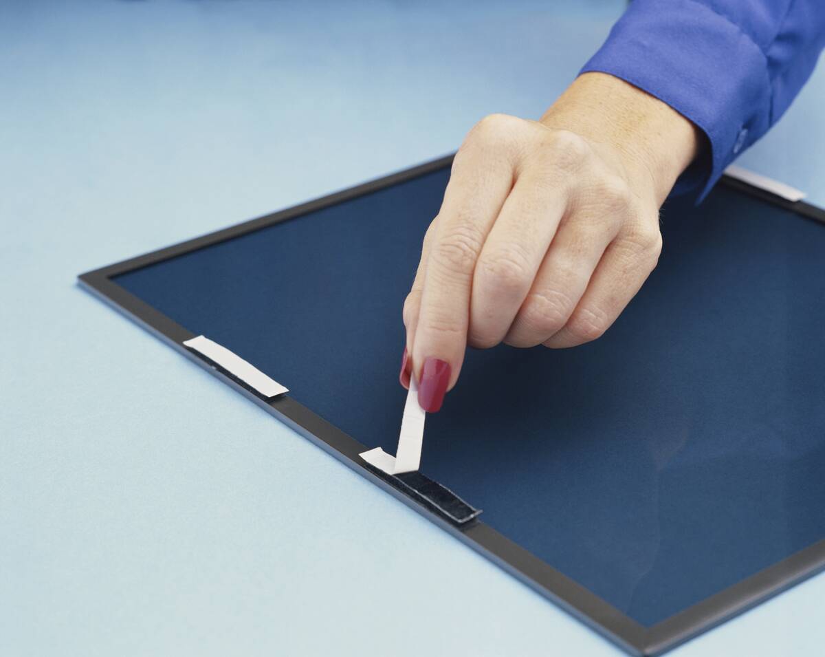 Woman removing sticky tape from computer screen