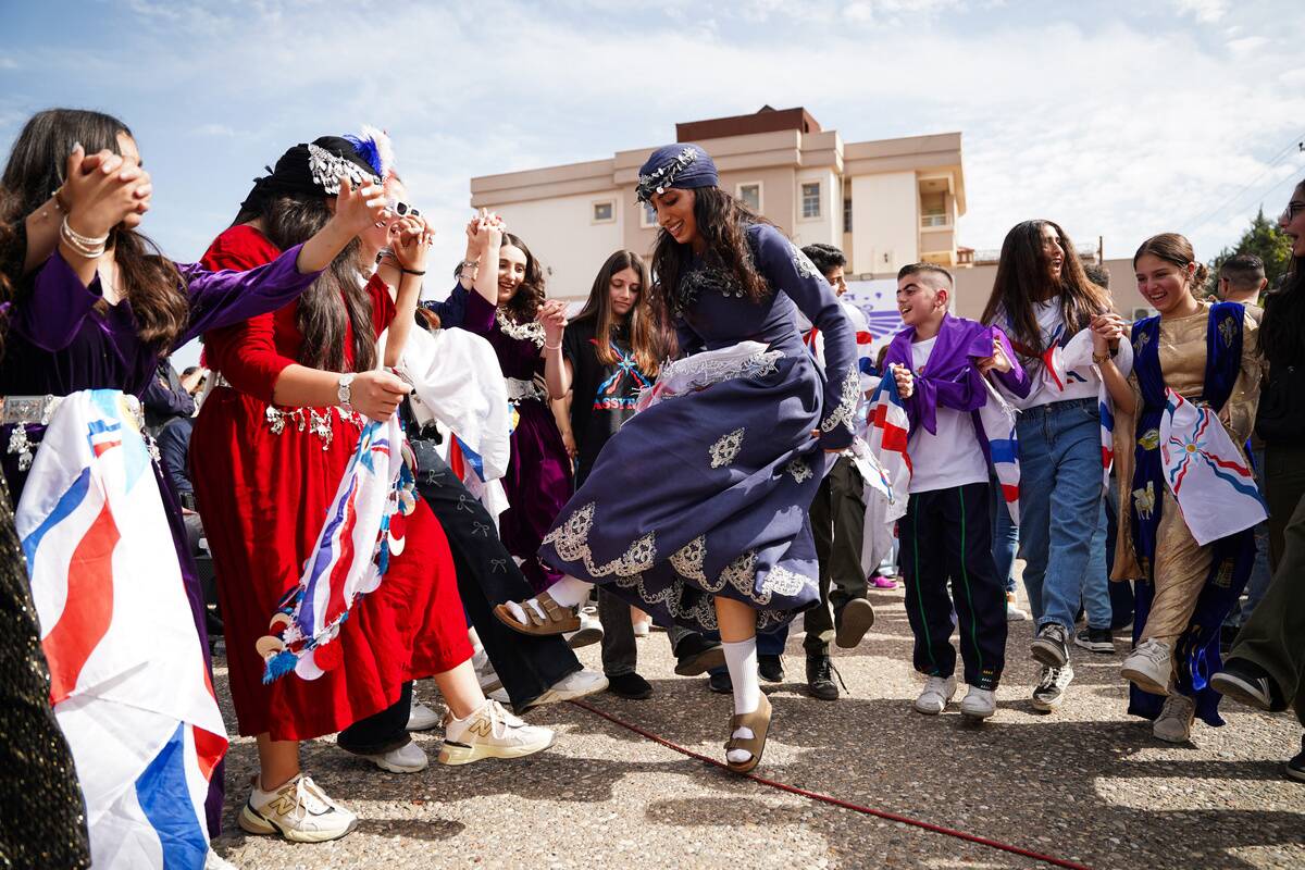An Assyrian woman dressed in traditional clothes is seen...