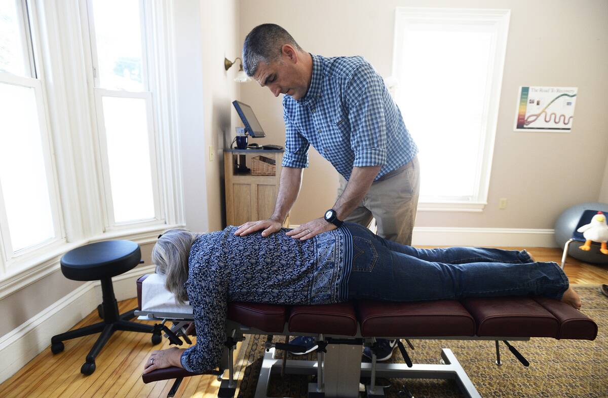 Dr. Robert Lavoie makes chiropractic adjustments to his patient Debra Labbe...